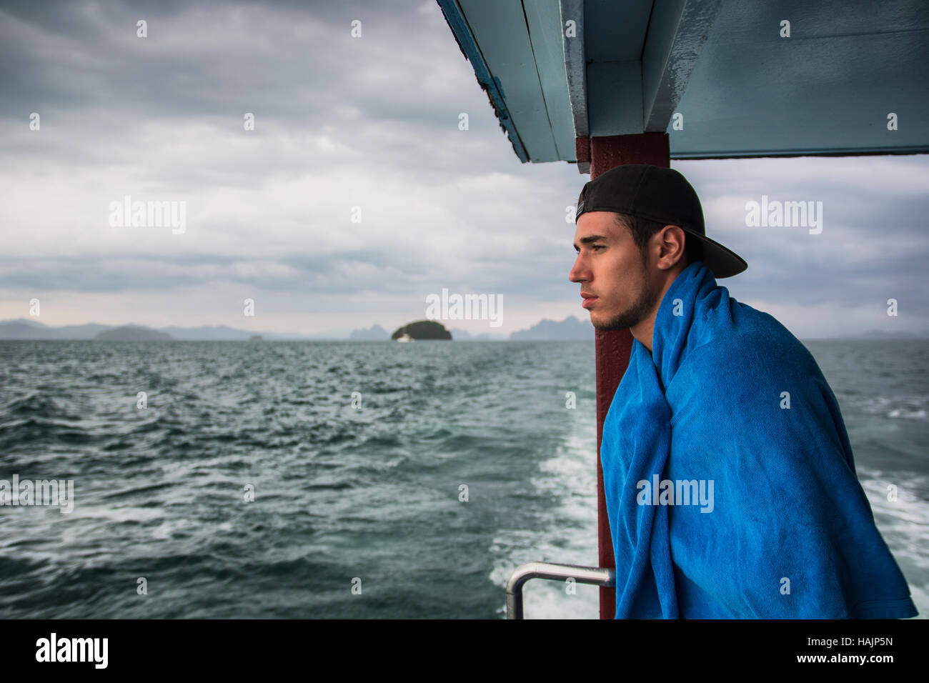 Profile shot of a man on a boat looking at an ocean over the railing Stock Photo