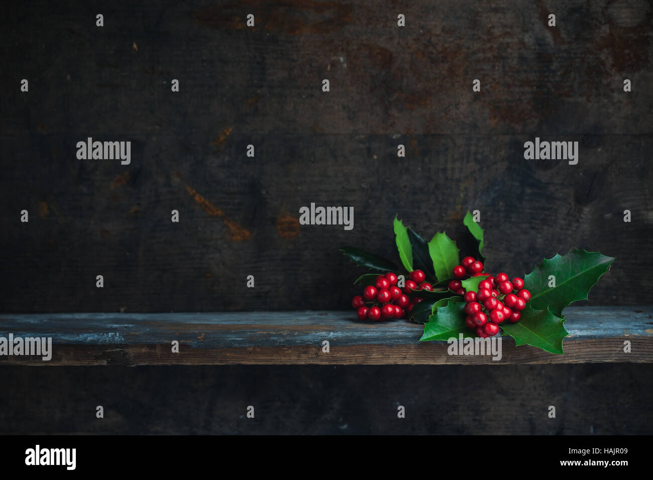 Christmas Holly Twig. Christmas decoration with red berries placed on a wooden shelf. Stock Photo