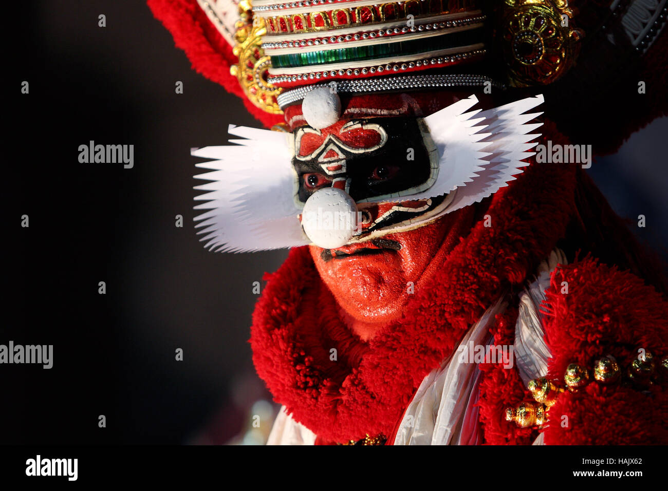 Kathakali dancer with a red face mask and make up usually worn by performers portraying villains Stock Photo