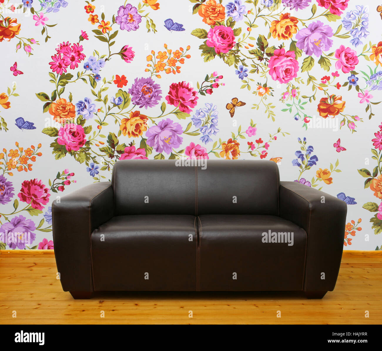 interior with brown leather couch against colorful floral wall Stock Photo