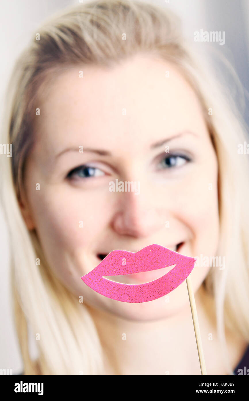 smiling woman with big paper lips in front of her mouth Stock Photo