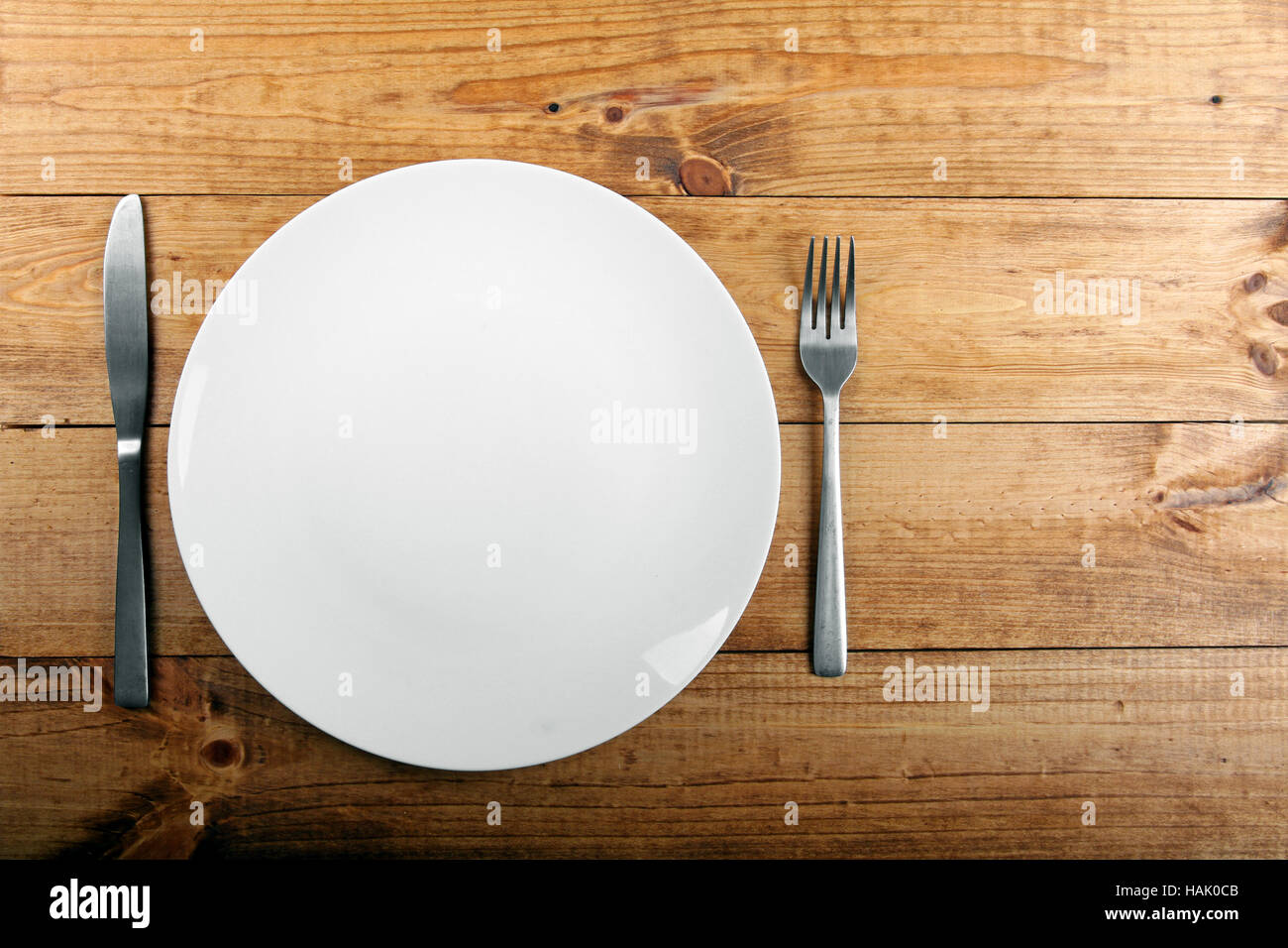 empty white plate on brown wooden table Stock Photo