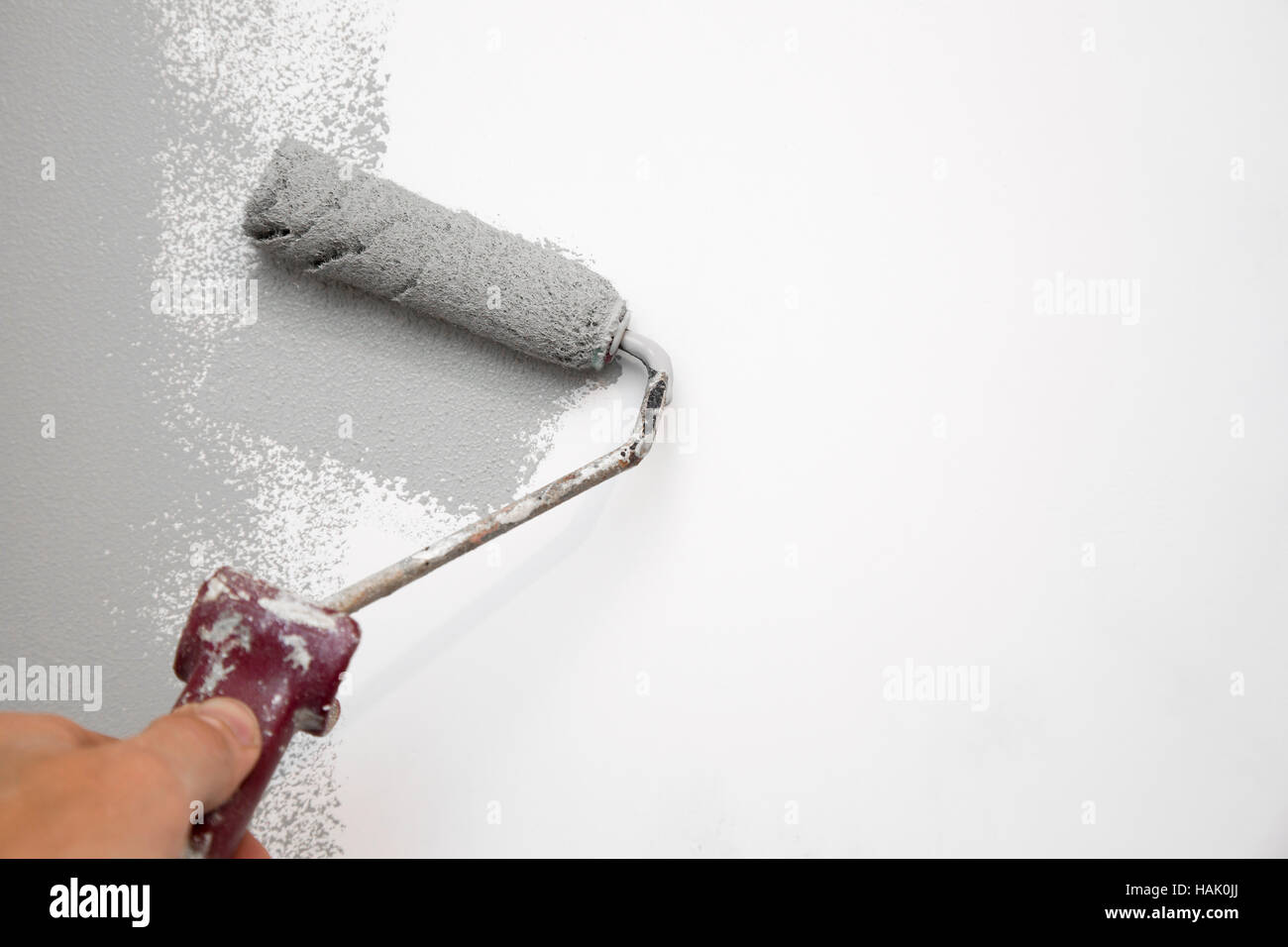 gray color painting wall with roller in hand Stock Photo