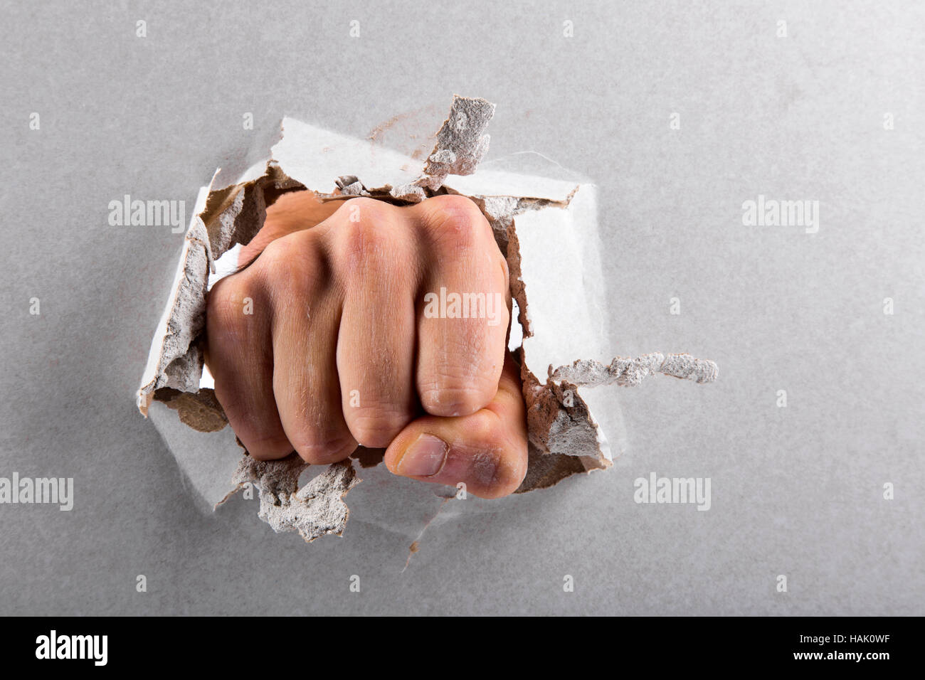 aggression concept, wall is broken through by a fist Stock Photo