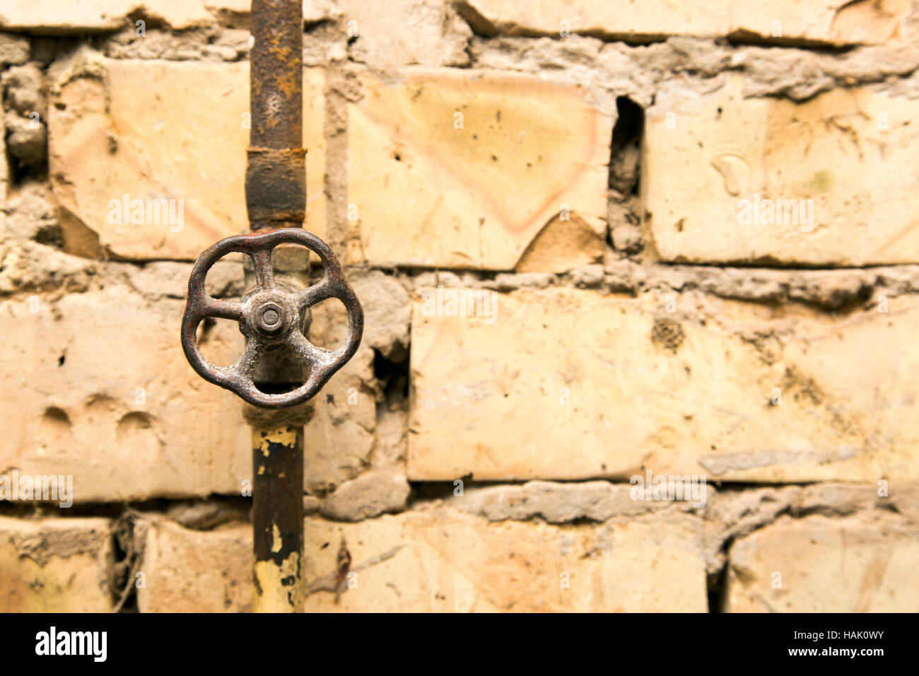 rusty pipeline valve on brick wall background Stock Photo