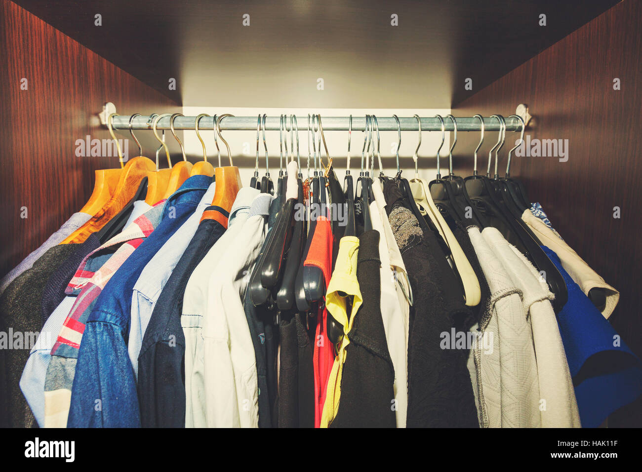 variety of clothes hanging in wooden wardrobe Stock Photo