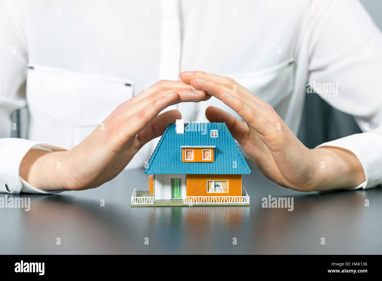 real estate insurance concept - human hands saving small house Stock Photo