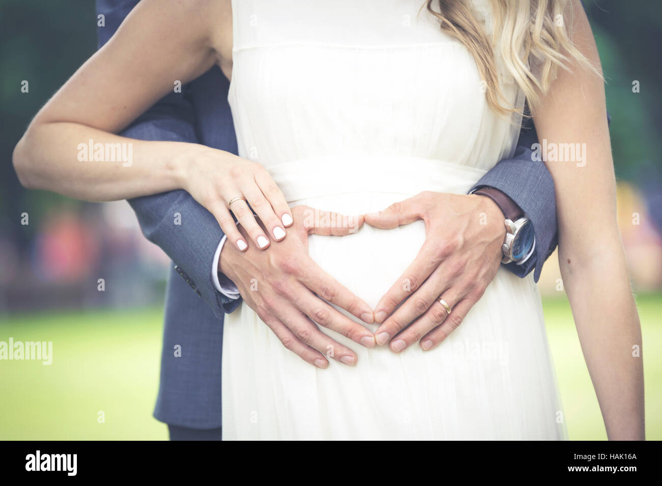newlyweds - heart shaped men's hands on woman's belly Stock Photo