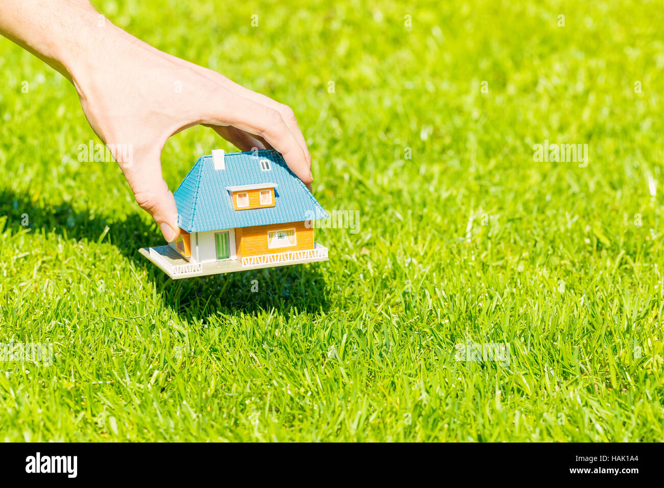 new home concept, hand putting house scale model on grass Stock Photo