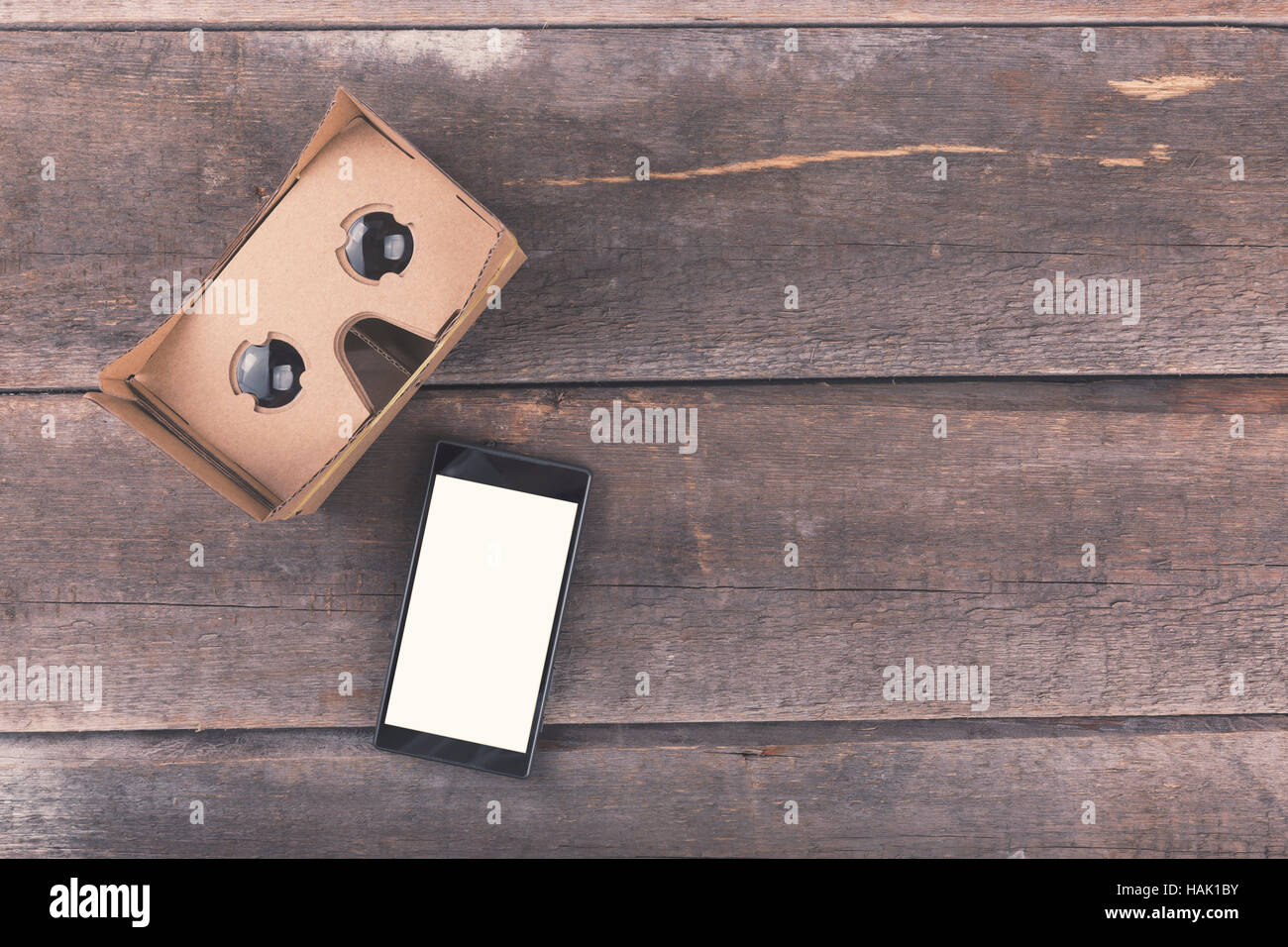 cardboard virtual reality glasses with blank smartphone on wooden background Stock Photo