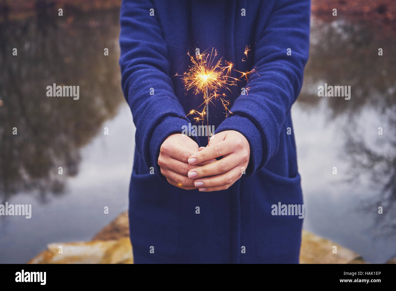 Woman holding sparkler in forest, winter day Stock Photo