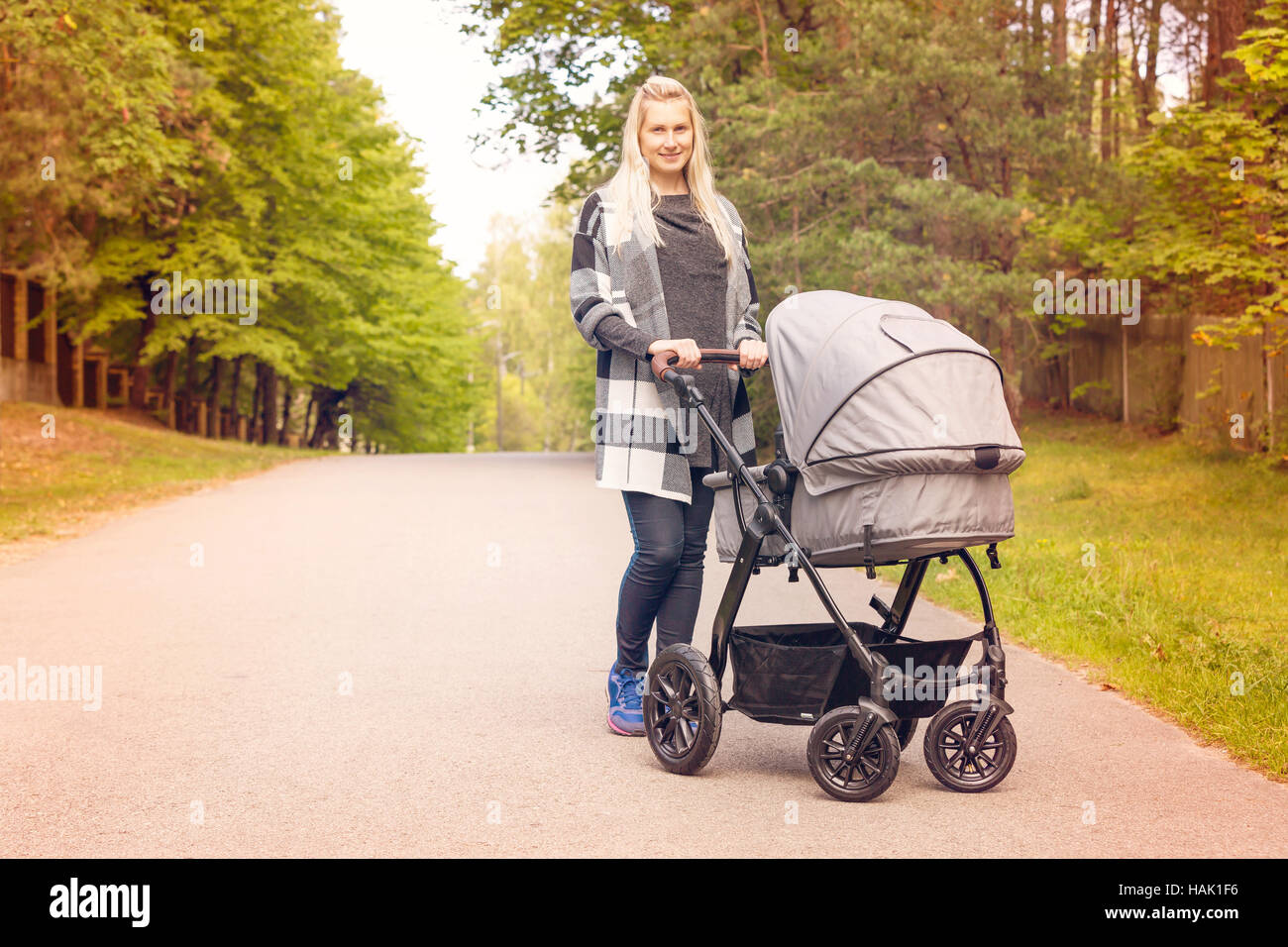 young happy mother with baby carriage on beautiful autumn day Stock Photo