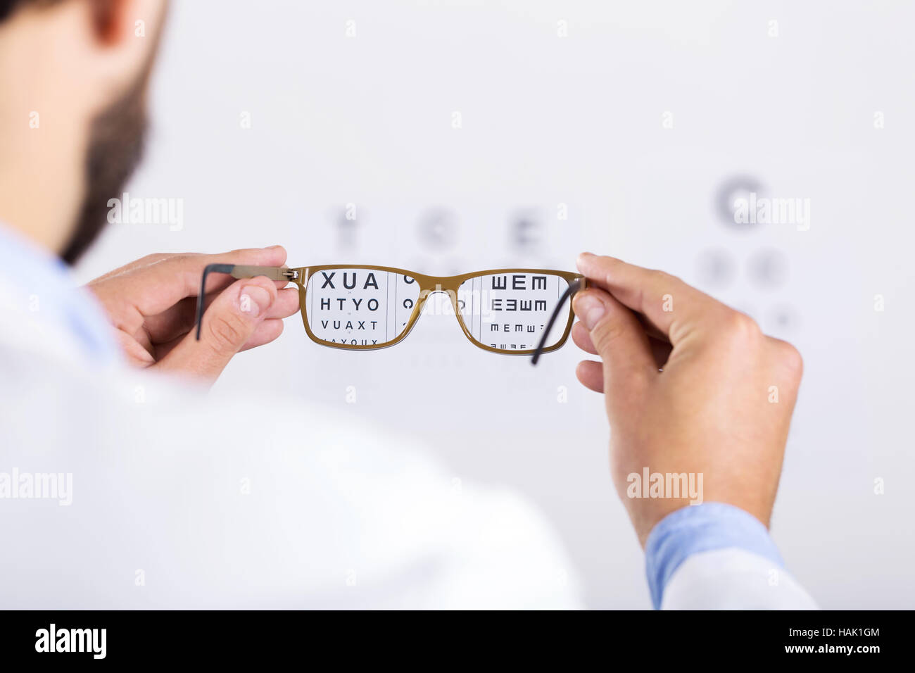optician holds glasses in front of eyesight test chart Stock Photo