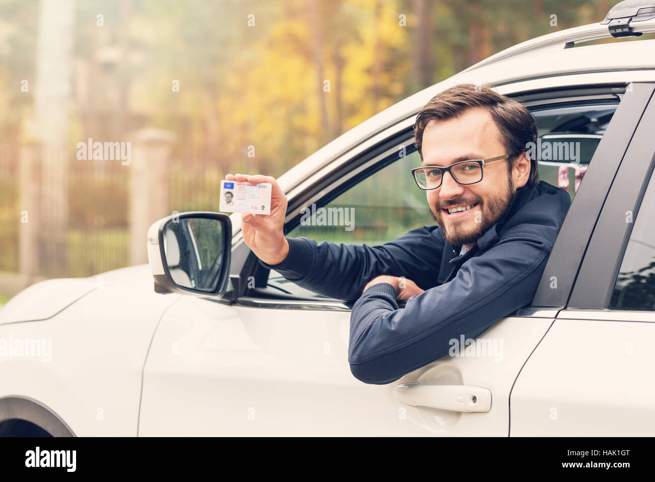 man sitting in the car and showing his driver license Stock Photo