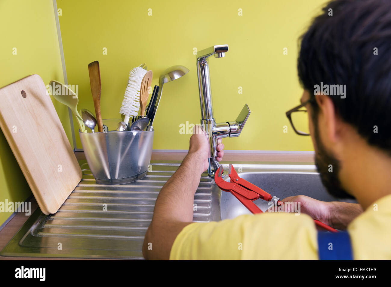 plumber installing, repairing water tap in kitchen Stock Photo Alamy