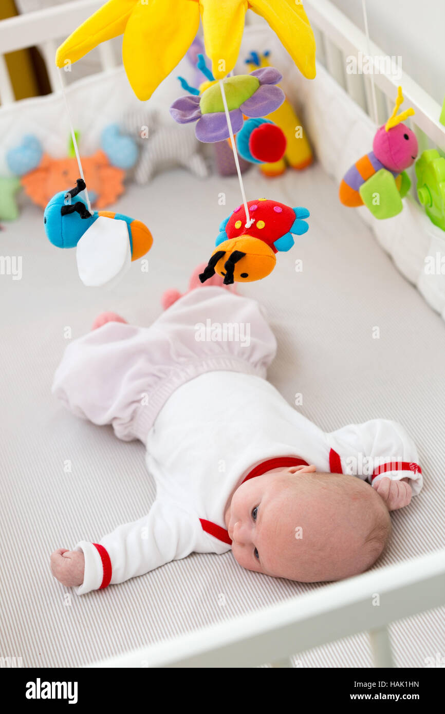 infant baby sleeping in the bed with stuffed toys hanging over Stock Photo