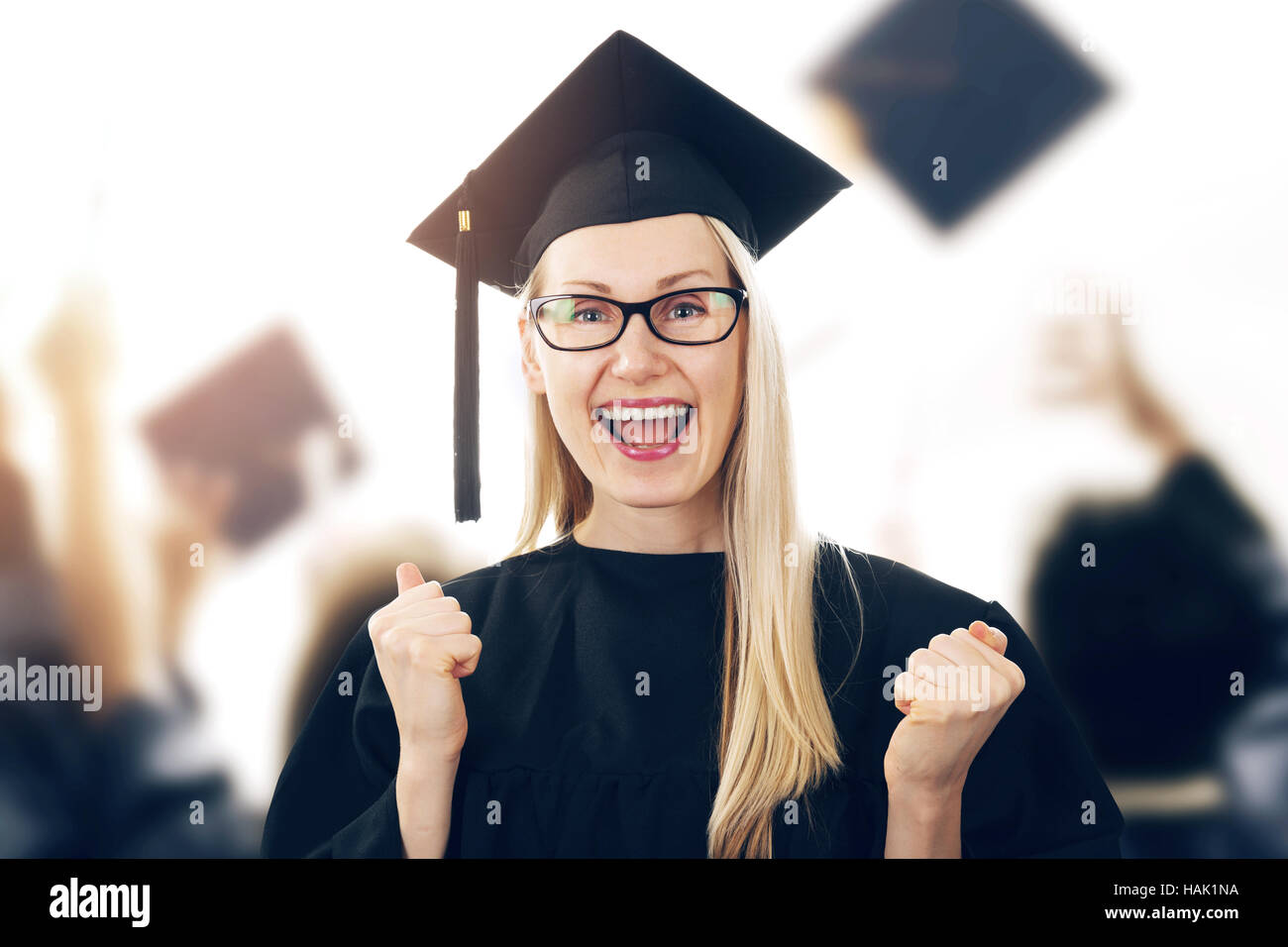 college graduation - happy woman wearing gown and cap celebrating Stock Photo