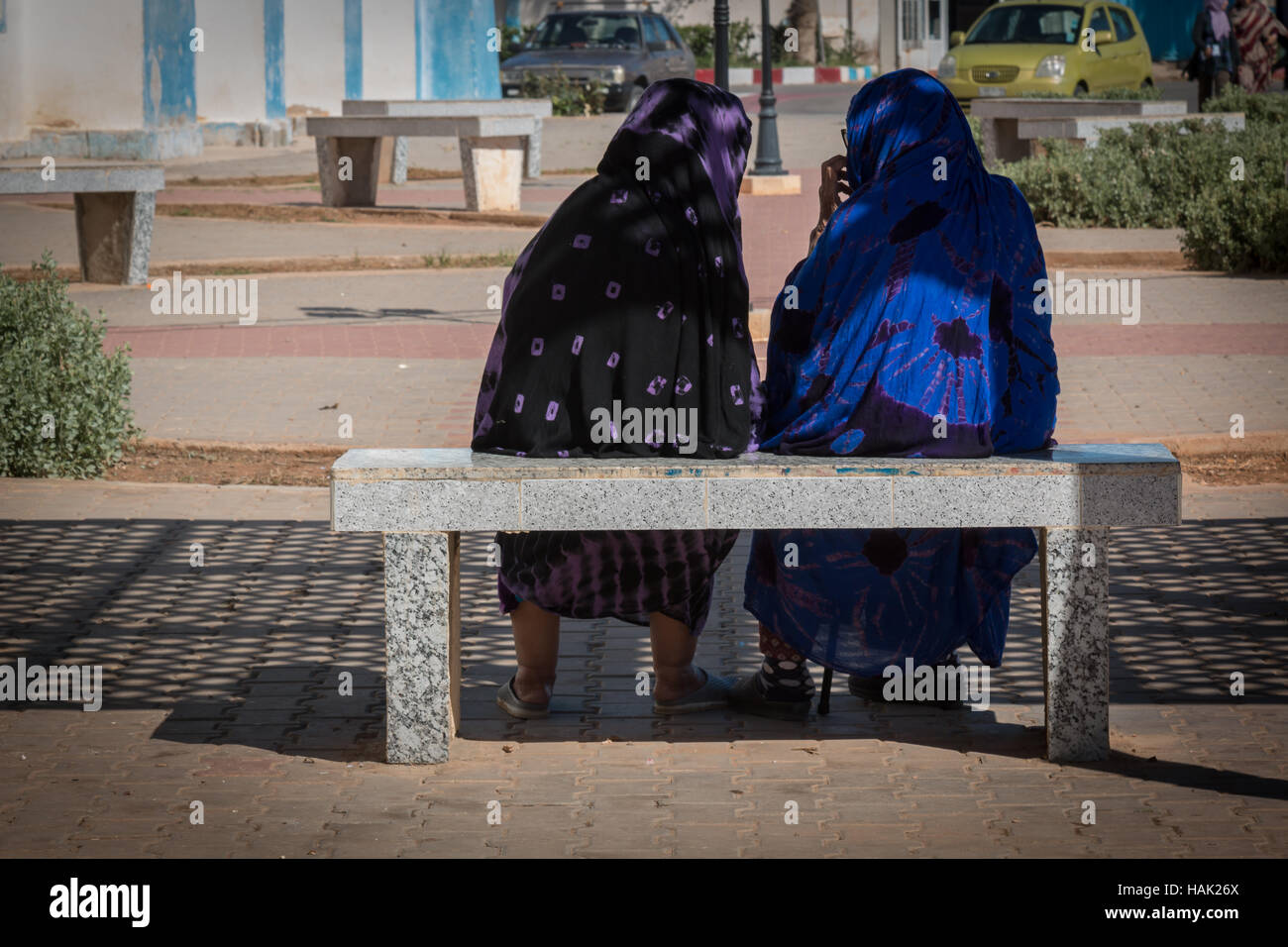 Relax on a bench during a hot summer day. Two arabian wreathed women talking while sitting on a bench. Stock Photo