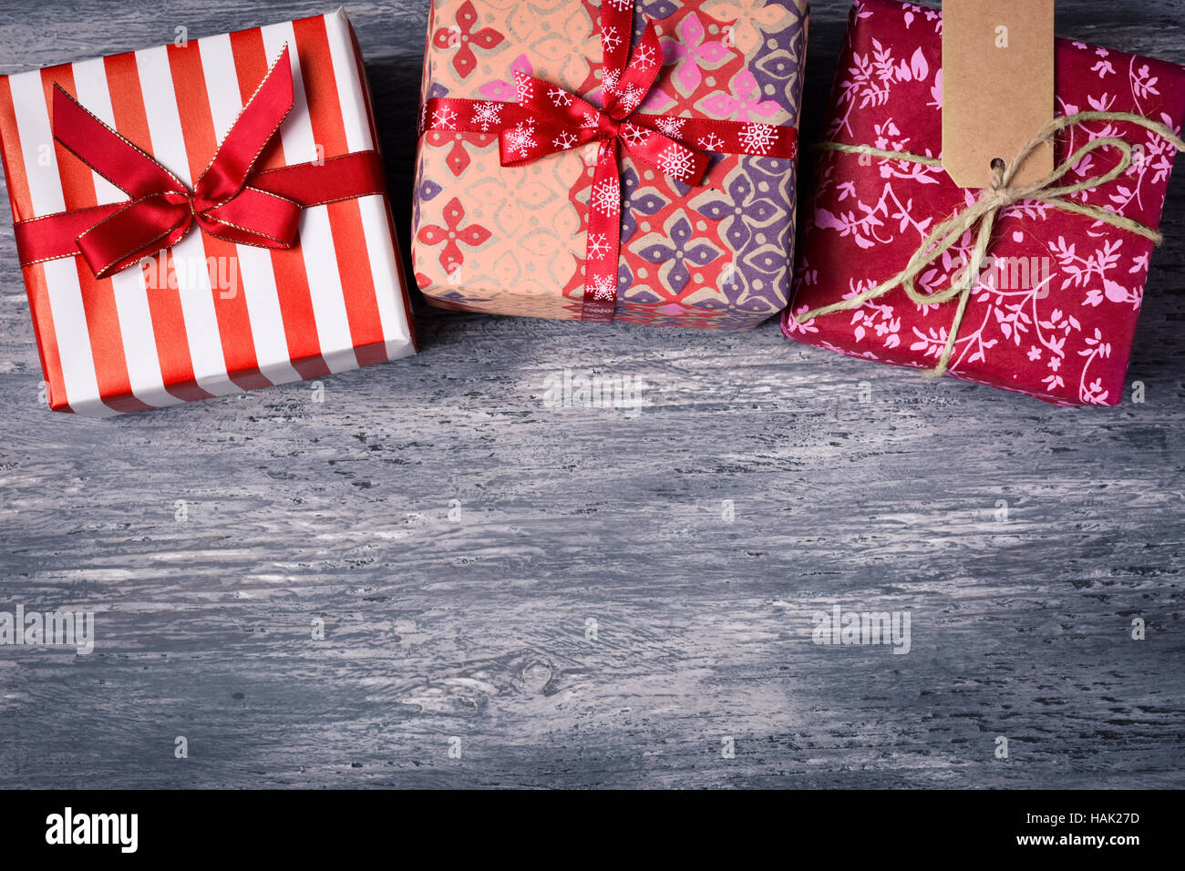 high-angle shot of some cozy gifts wrapped in different nice papers and tied with ribbons and strings of different colors on a rustic wooden surface, Stock Photo