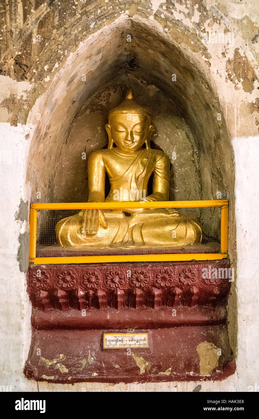 A small golden statue of The Buddha in an alcove at Thatbyinnyu Temple. Built in the 12th century, Thatbyinnyu Temple is one of the more prominent temples in the Bagan Archeological Zone and stands adjacent to the famous Ananda Temple. Stock Photo