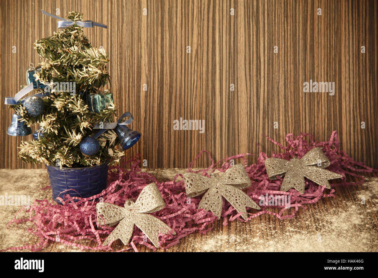 small manmade Christmas tree with toys and bows on wooden background
