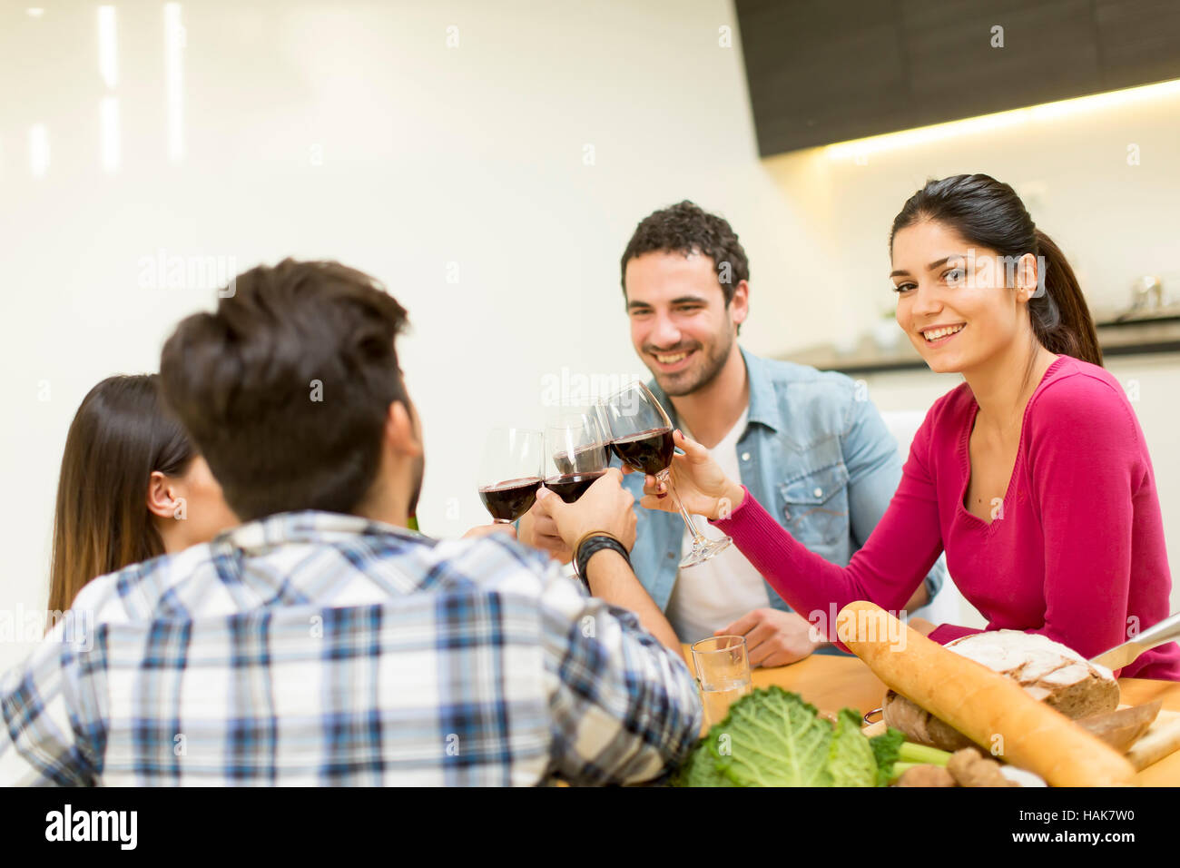 Group of happy young people sitting by the table eating and drinking red wine Stock Photo Alamy