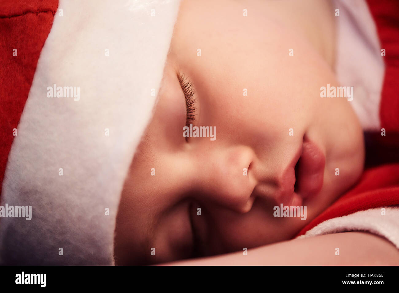 Close up of sleeping baby's face in santa outfit Stock Photo