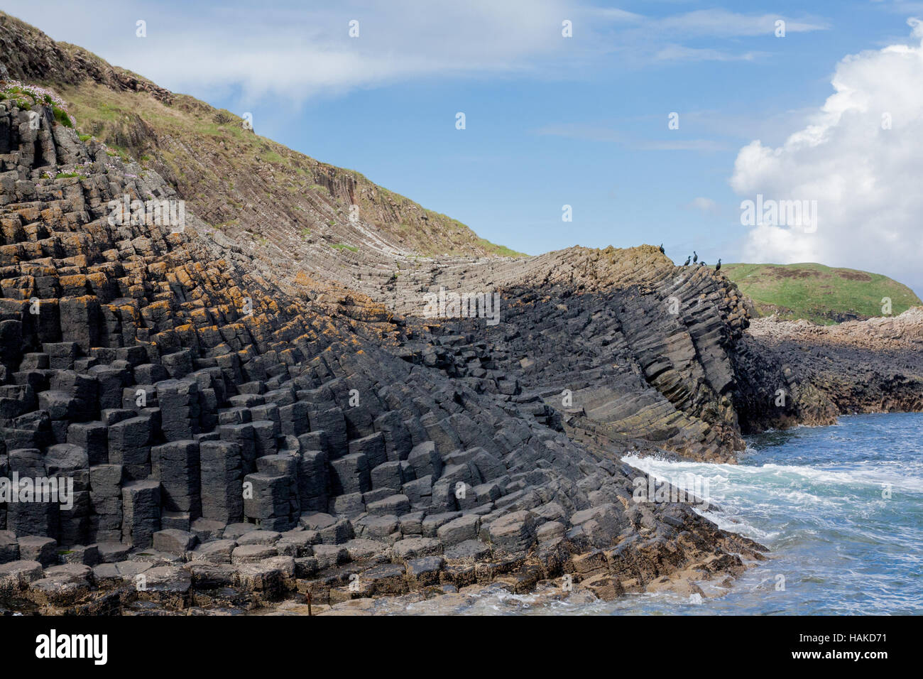 Sweeping basalt column rock formations on the Isle of Ulva coastline, Scotland, with defined intertidal zones Stock Photo
