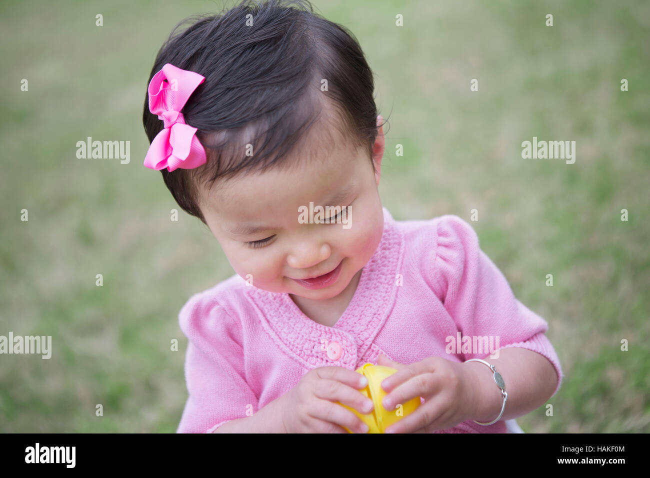 Toddler Girl Smiling while she Opens an Easter Egg Stock Photo