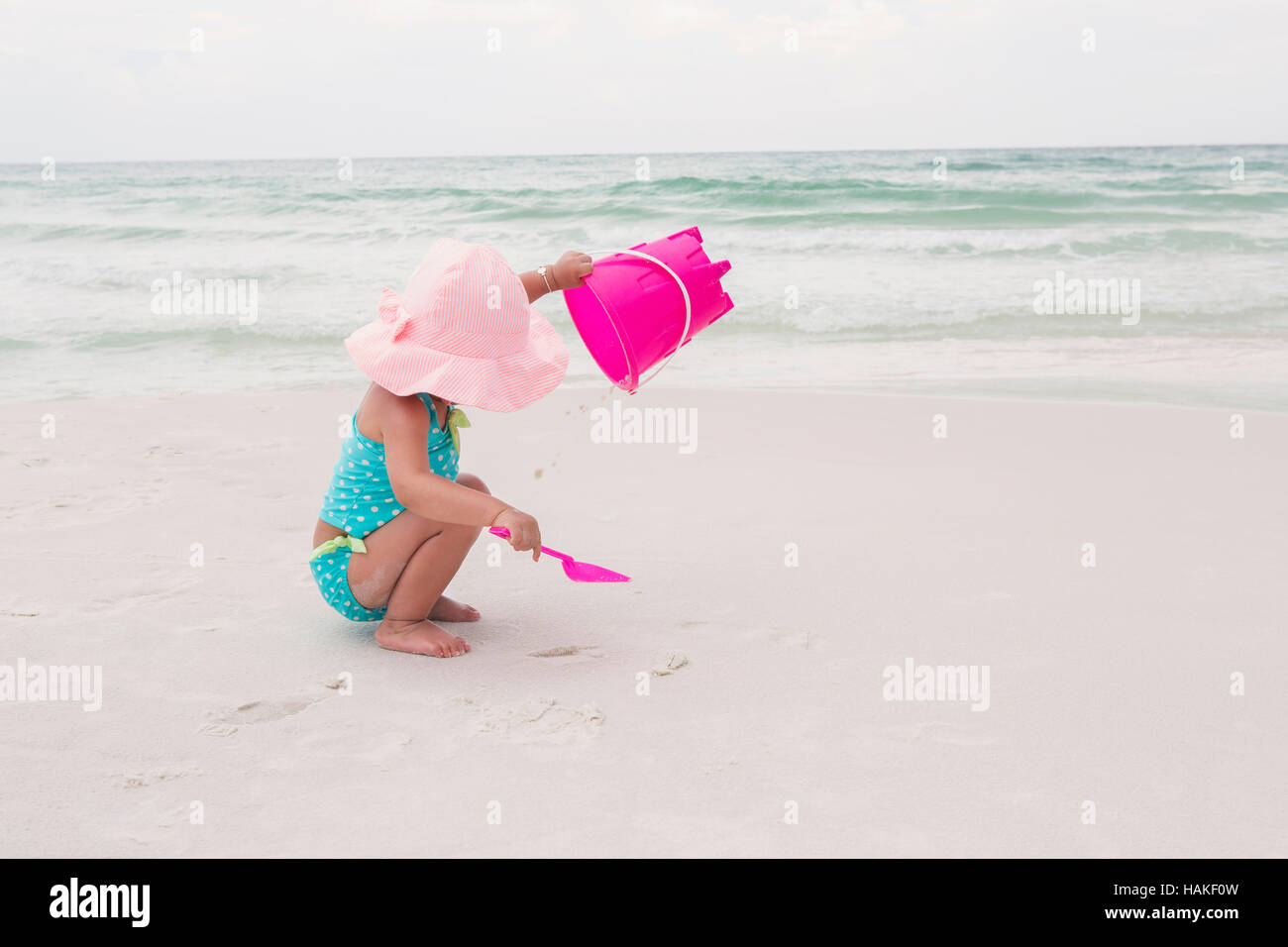Toddler Girl Playing with Shovel and Bucket in Sand on Beach, Destin, Florida, USA Stock Photo