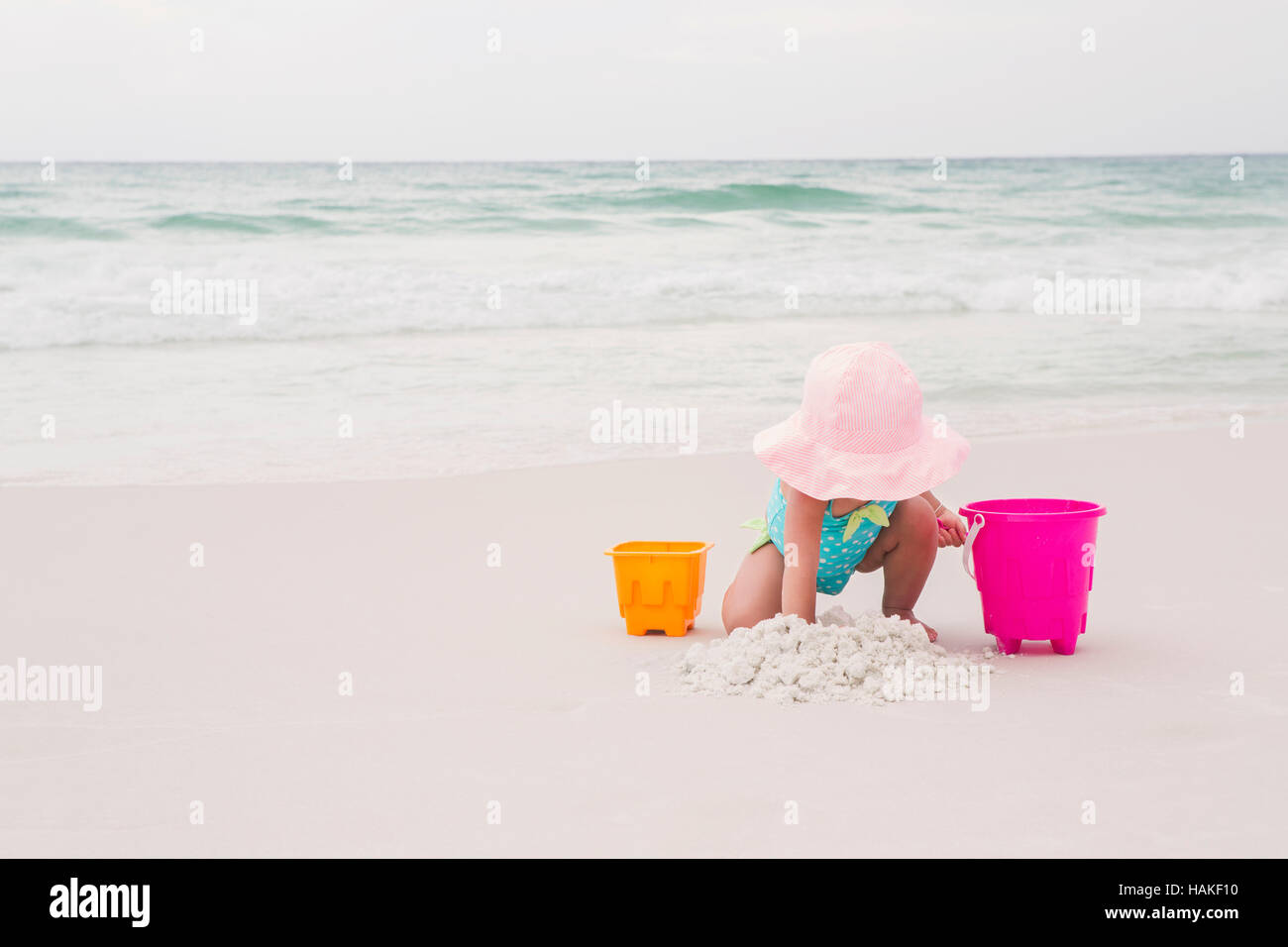 Toddler Girl Playing with Shovel and Bucket in Sand on Beach, Destin, Florida, USA Stock Photo