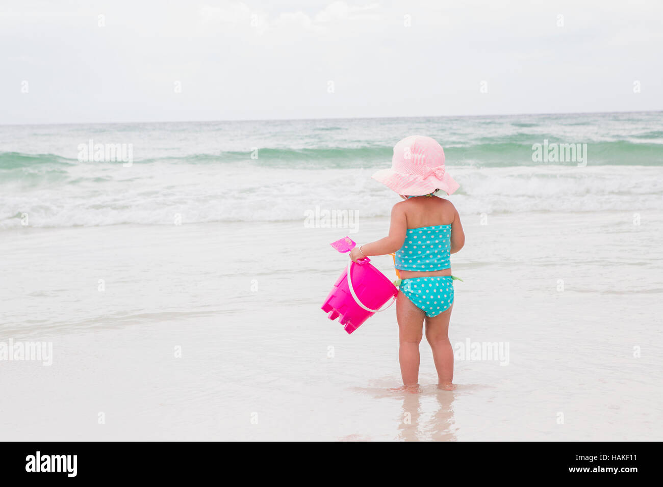 Toddler Girl Playing in Ocean with Shovel and Bucket at Beach, Destin, Florida, USA Stock Photo