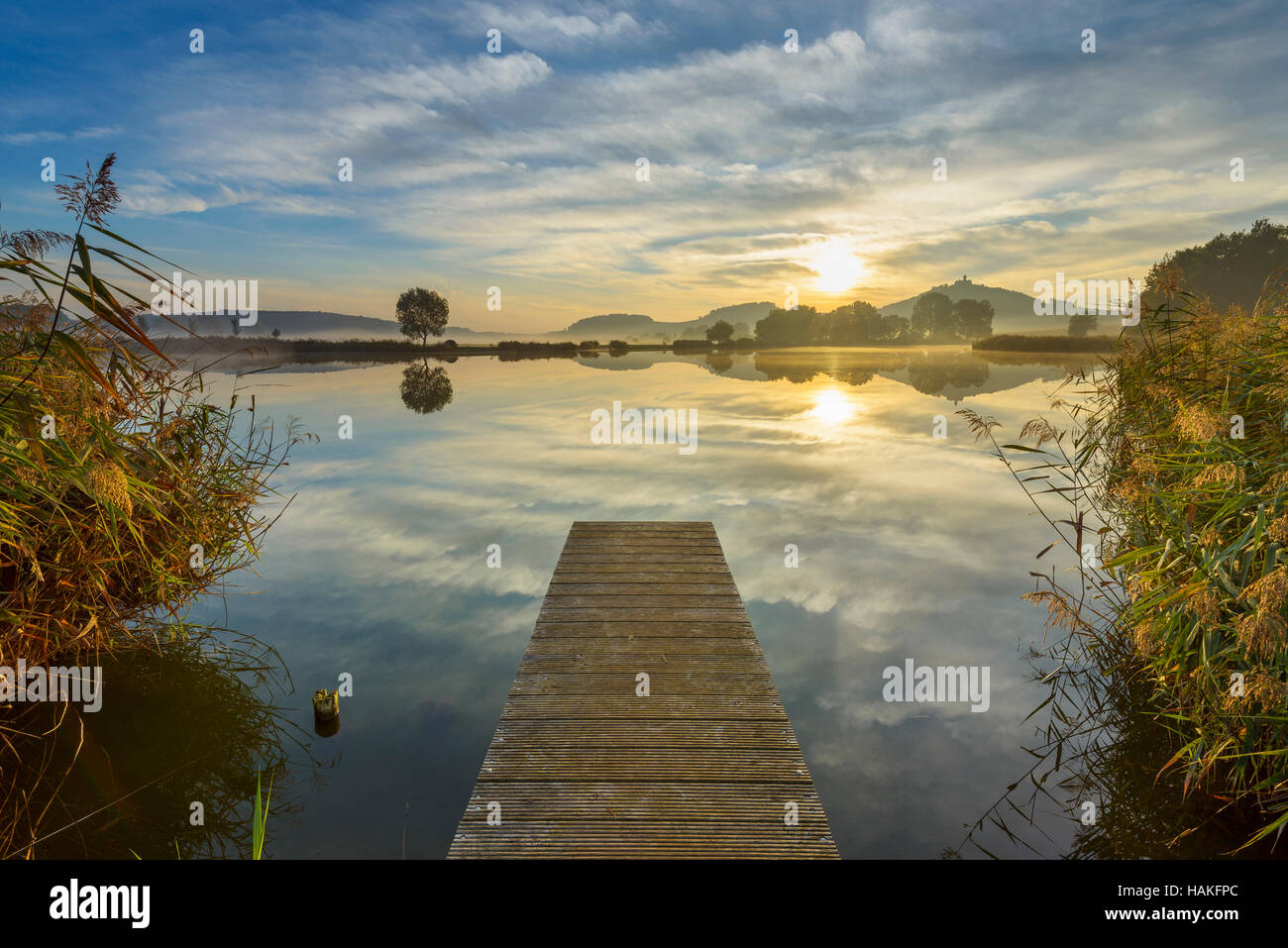 Wooden Jetty with Reflective Sky in Lake at Sunrise, Drei Gleichen, Ilm District, Thuringia, Germany Stock Photo