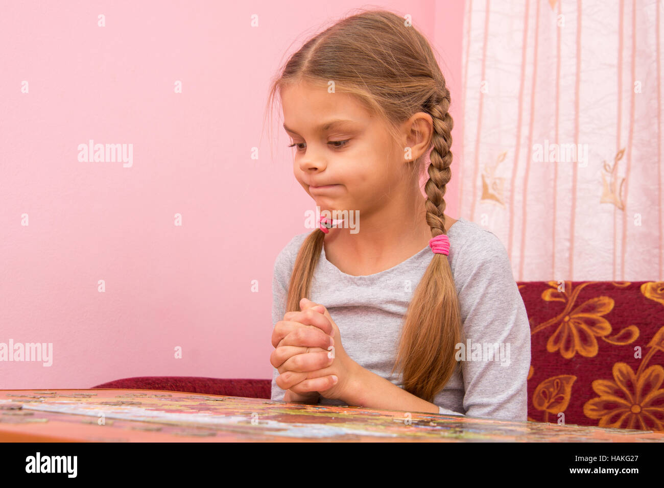 Girl funny thought pouting cheeks collecting picture of puzzles Stock Photo