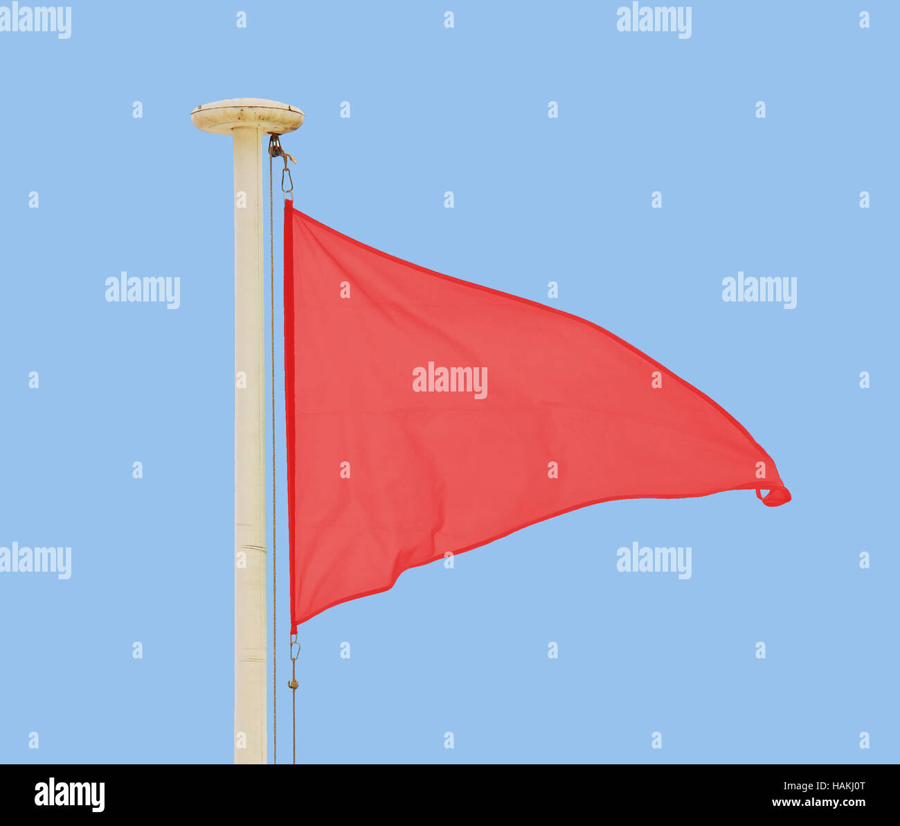 Red pennant flying in a brisk breeze against a pale blue sky Stock Photo