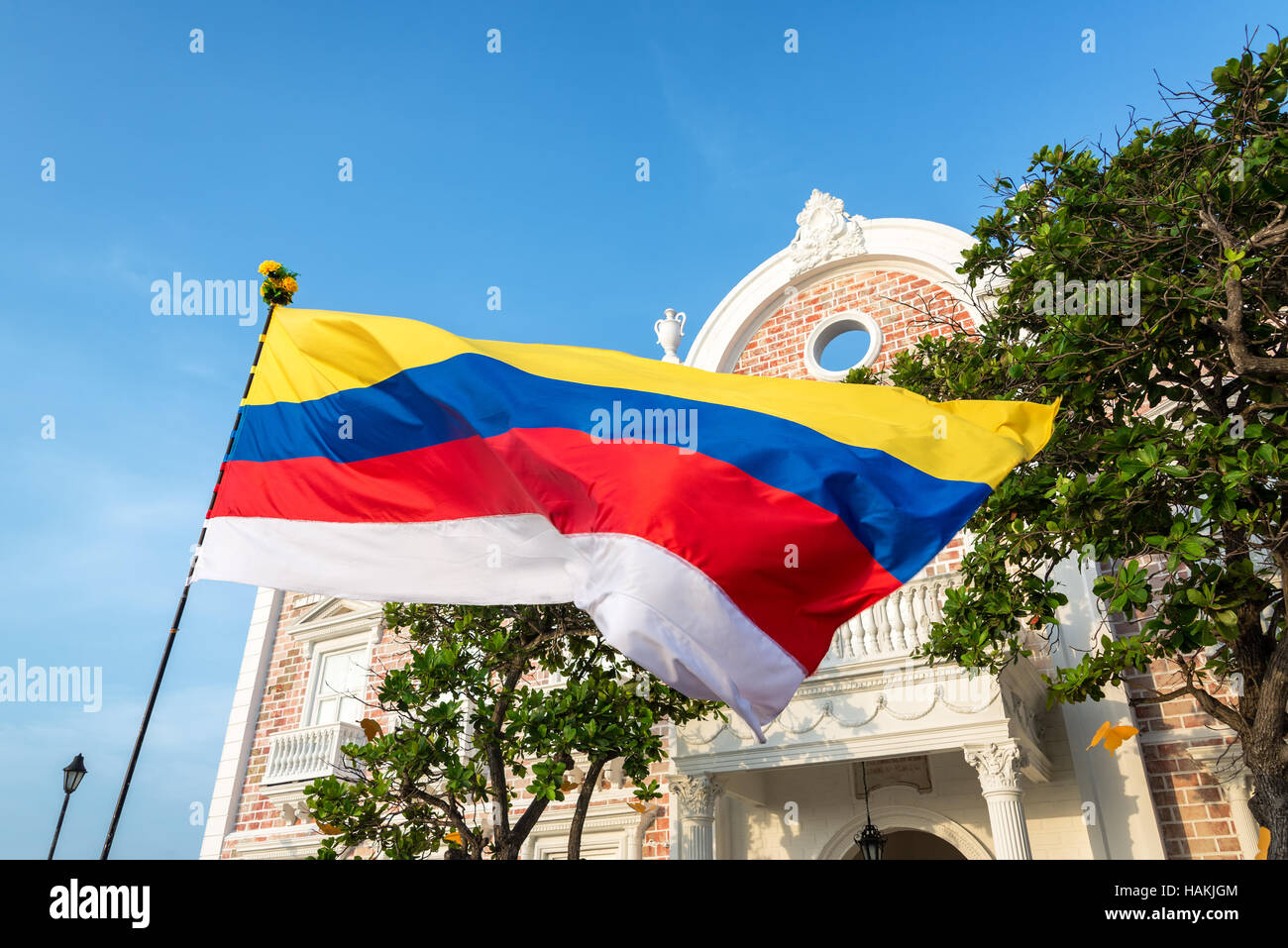 Colombian flag waving in front of a historic building in Cartagena, Colombia.  The white stripe has been added to symbolize the peace process Stock Photo