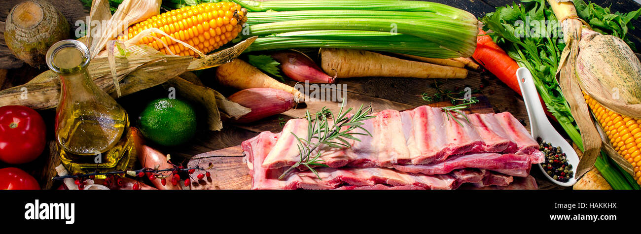 Raw beef ribs and vegetables on a dark wooden background. View from above Stock Photo