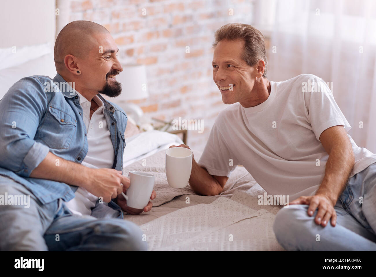 delighted-gay-couple-lying-on-the-bed-and-drinking-tea-HAKM66.jpg