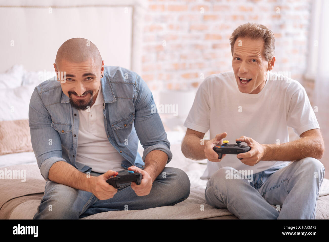 Amused friends playing with game console on the bed Stock Photo