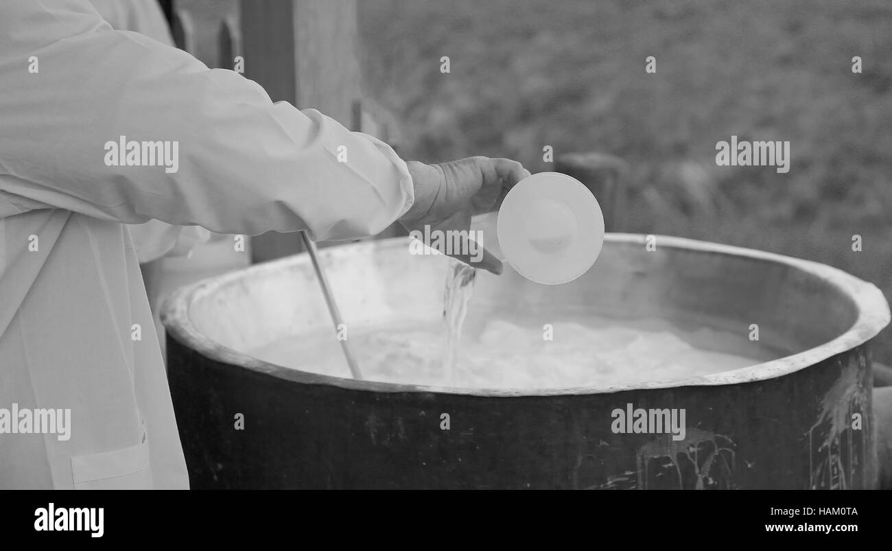 cheesemaker pour rennet into big cauldron to produce cheese in the dairy Stock Photo