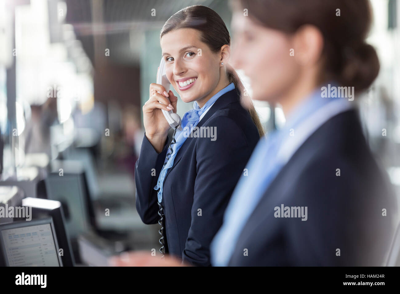Portrait smiling customer representative talking on telephone at airport check-in counter Stock Photo