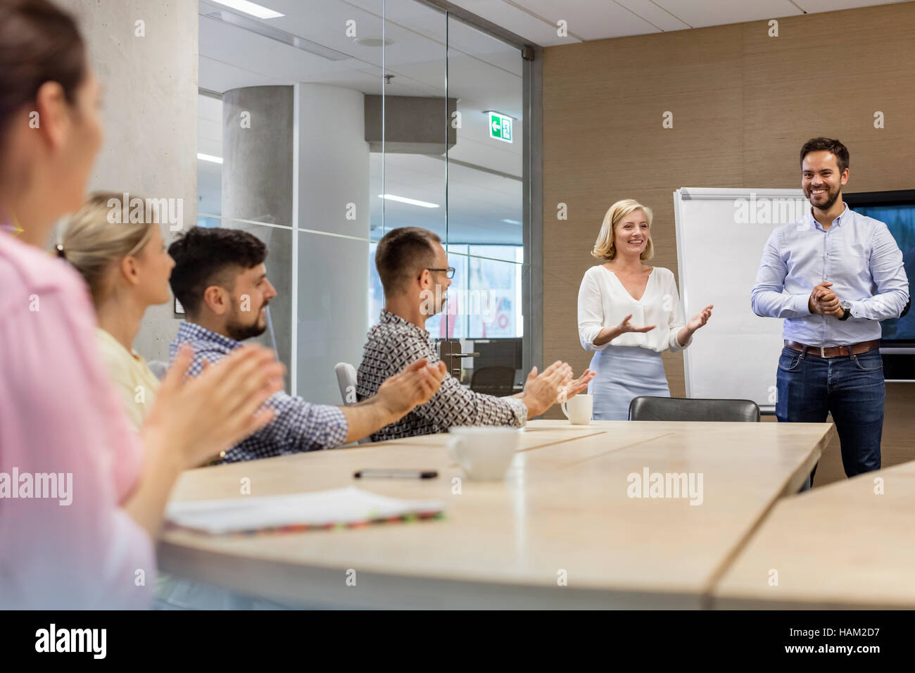 Business people clapping for businessman in conference room meeting Stock Photo