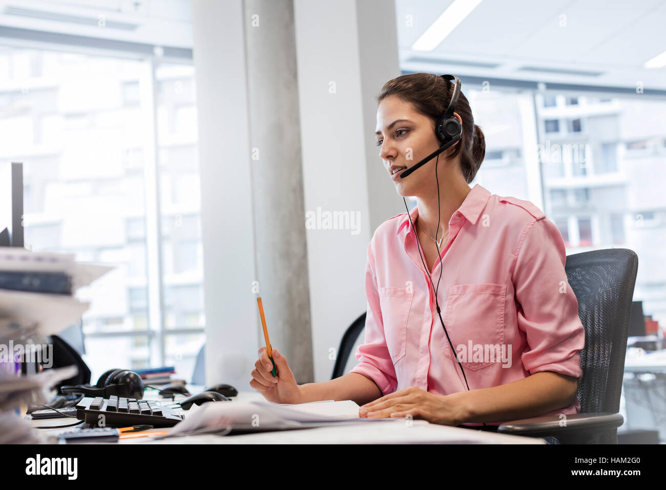 Businesswoman with hands-free device talking on telephone at office desk Stock Photo