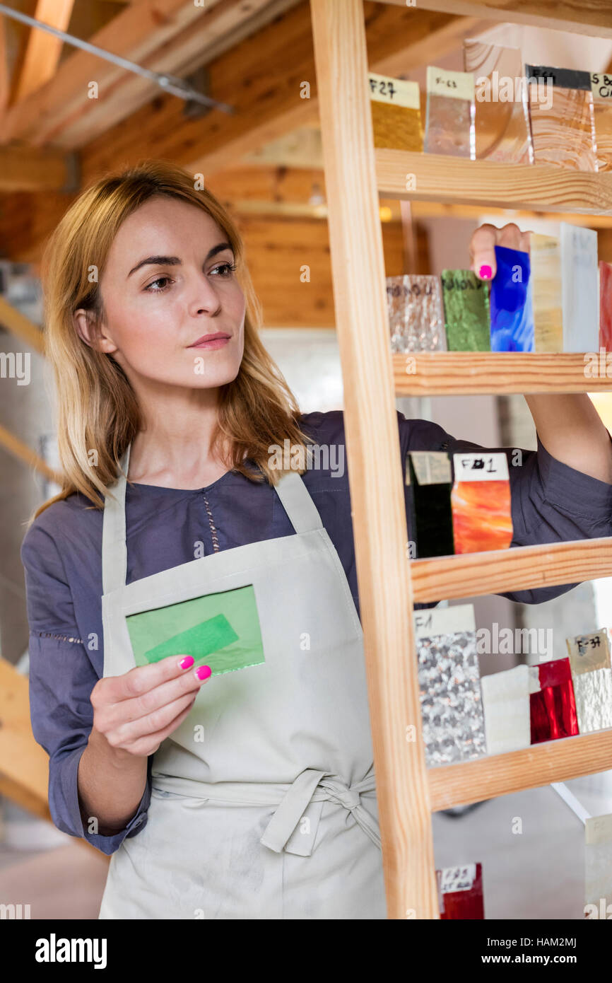 Stained glass artist examining glass pieces in studio Stock Photo