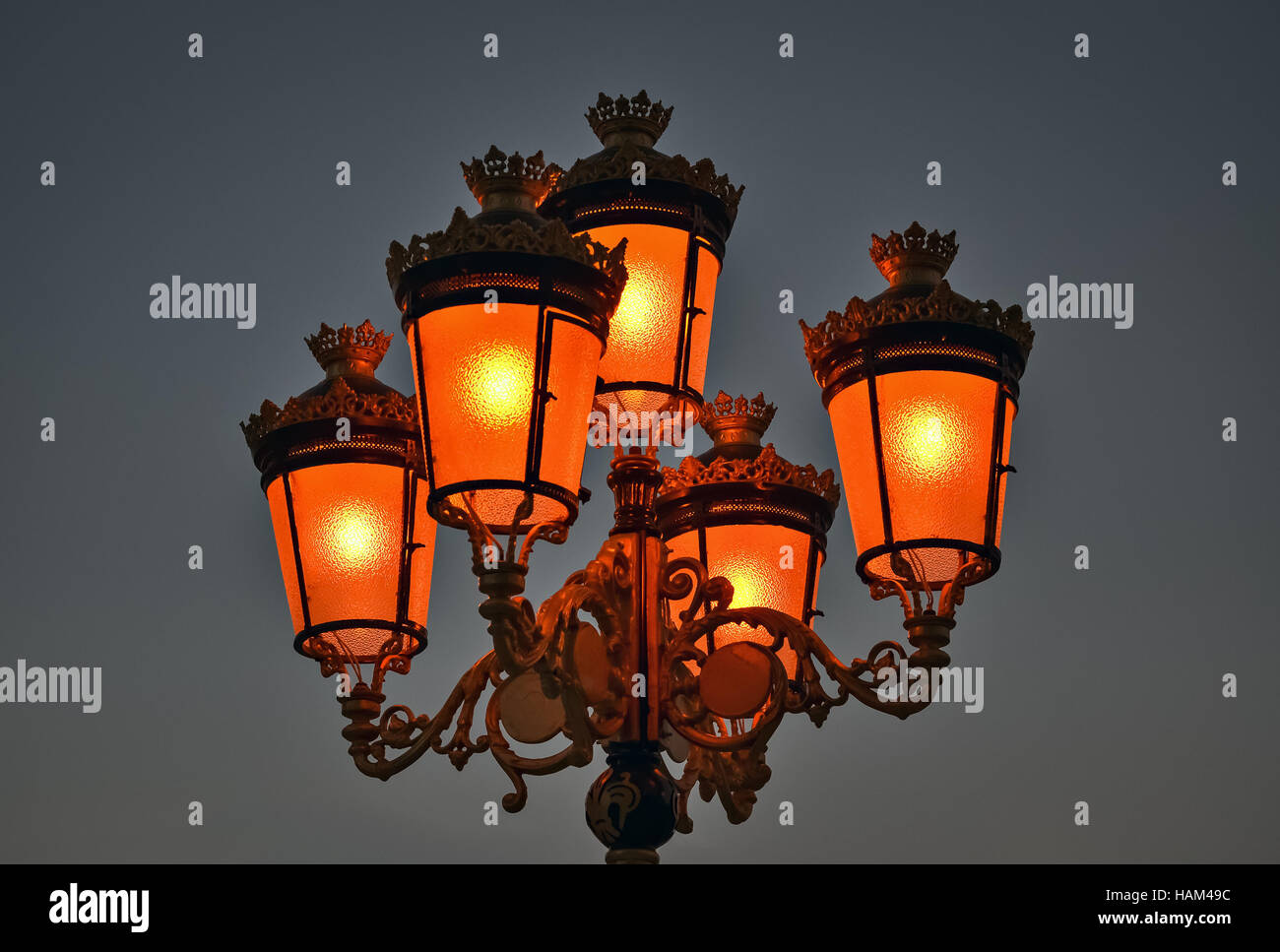 Closeup of a street light with five bulbs glowing in orange color Stock