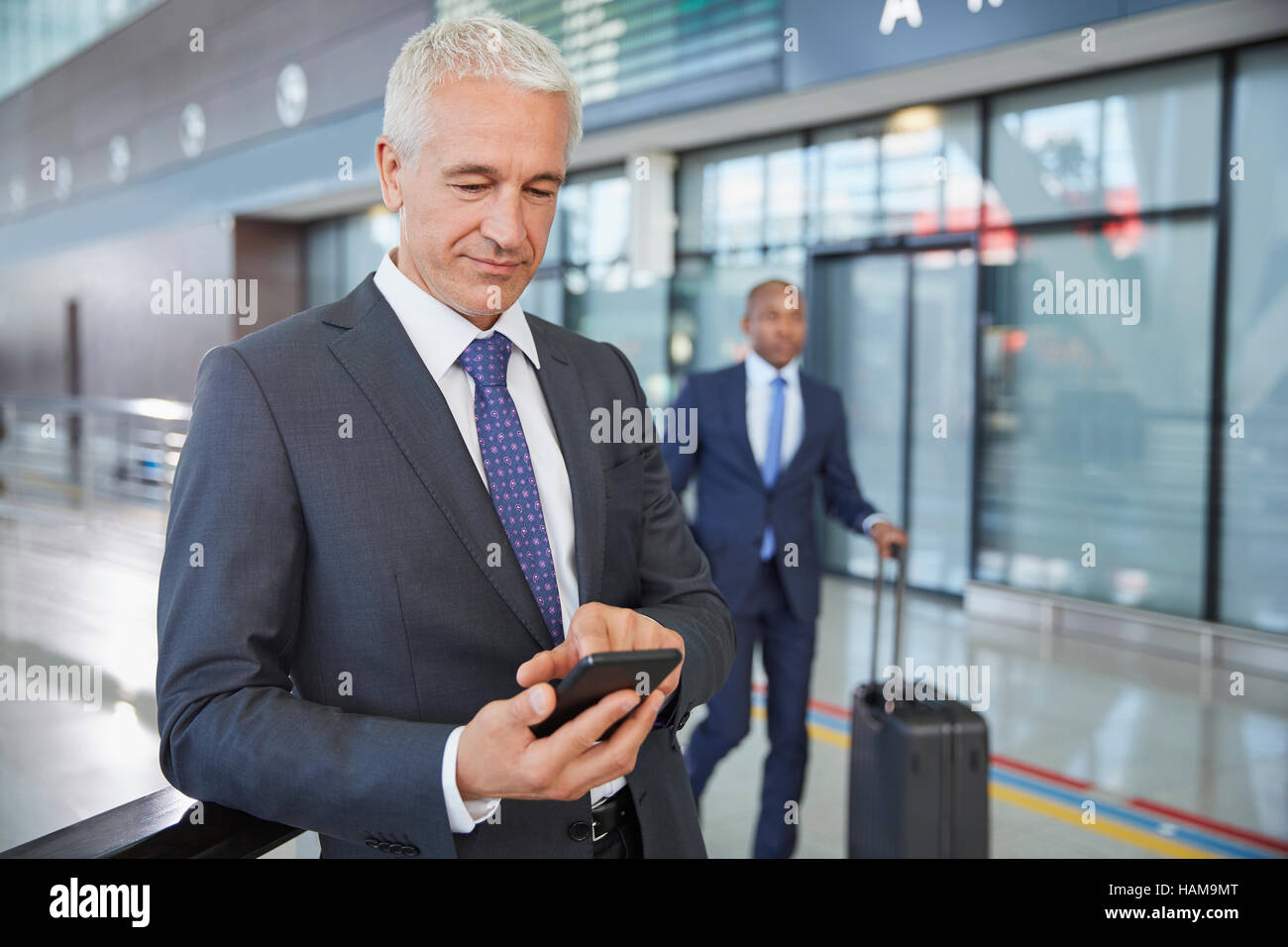 Businessman texting with cell phone in airport concourse Stock Photo