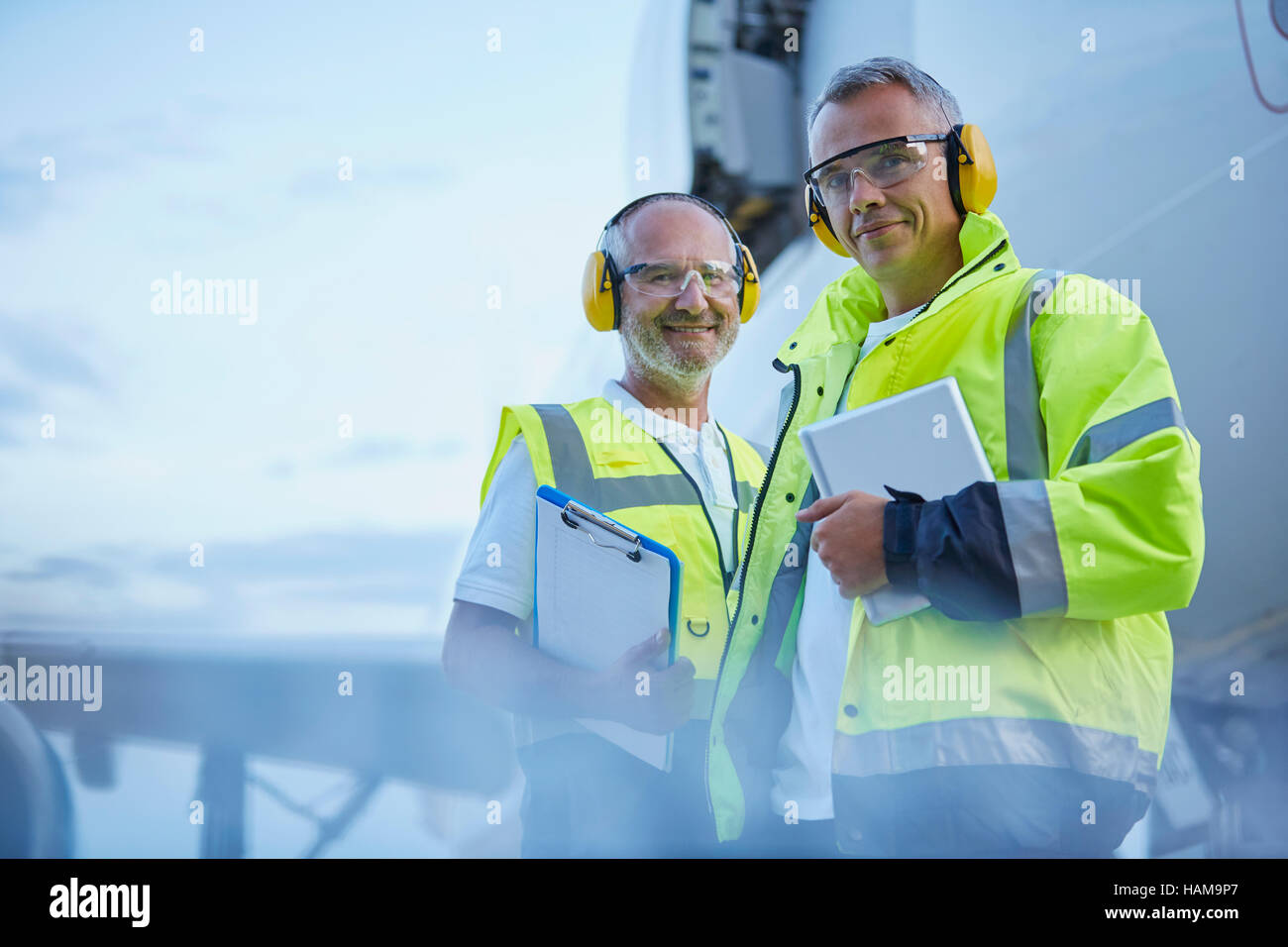 Portrait confident air traffic control ground crew workers with digital tablet near airplane on tarmac Stock Photo