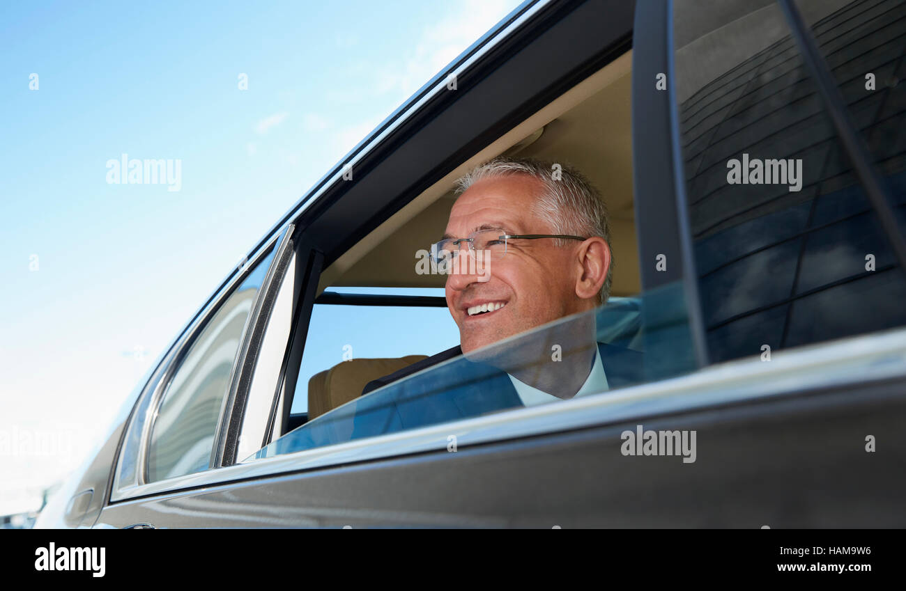 Smiling businessman looking out town car window Stock Photo