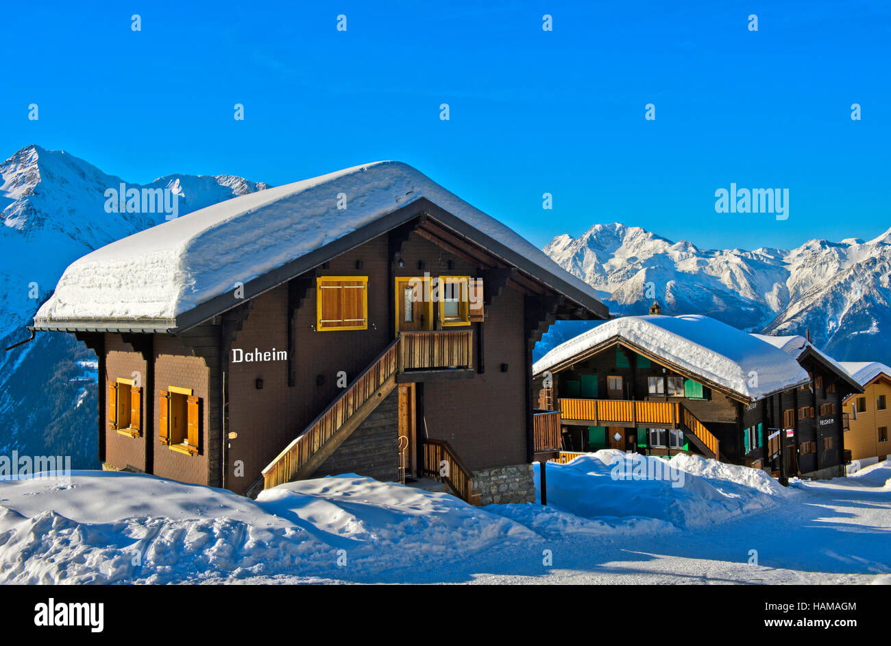 Swiss chalet with a thick layer of snow on the roof with Fletschhorn, Bettmeralp, Valais, Switzerland Stock Photo