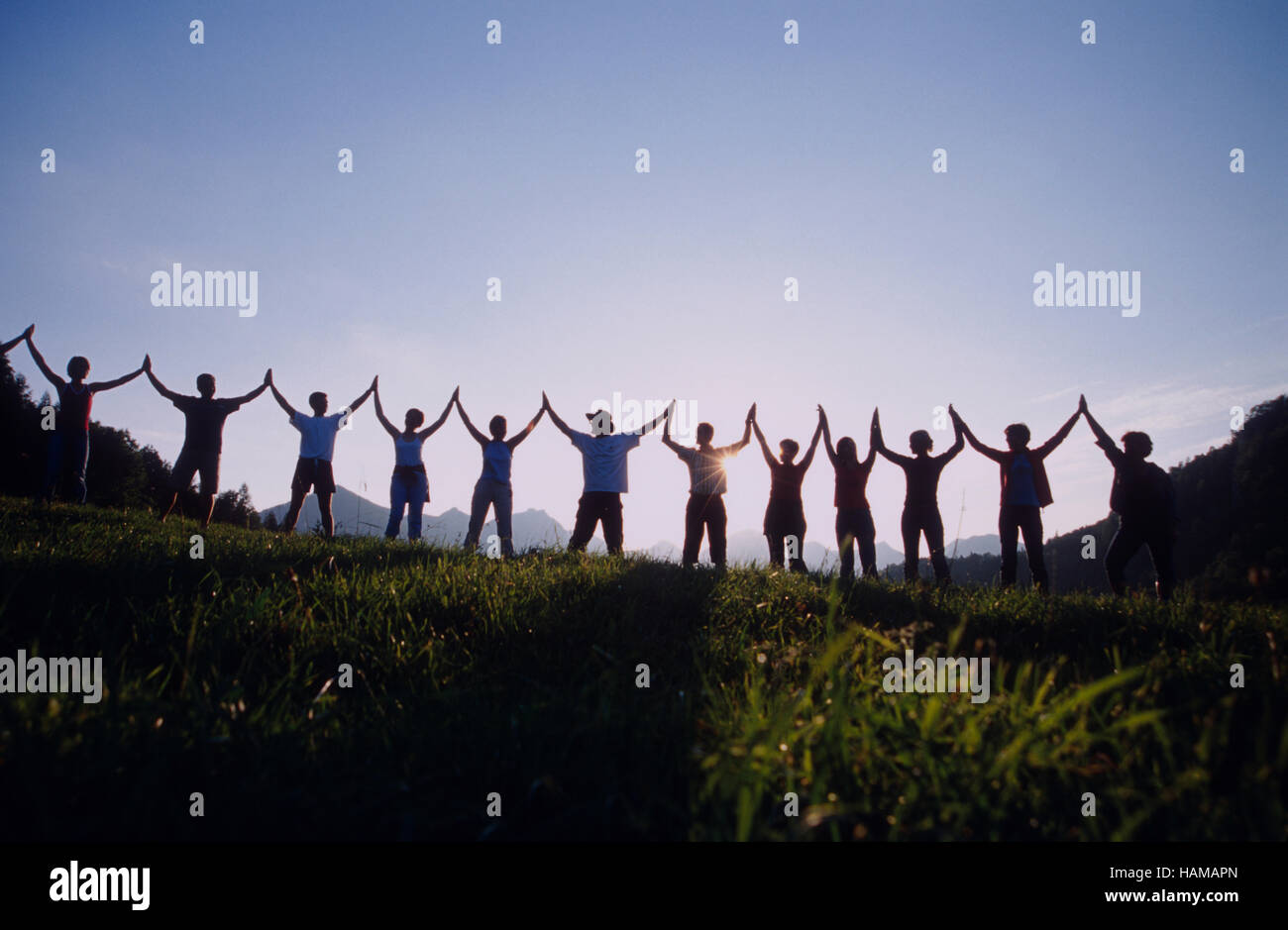Human chain in front of the sunset, Reichraming, Upper Austria, Europe Stock Photo